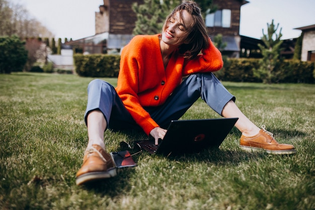 Jonge zakenvrouw met laptop op het gras