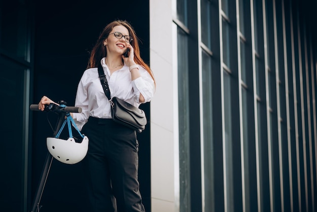 Jonge zakenvrouw scooter rijden en het gebruik van telefoon