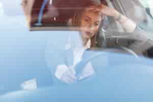 Gratis foto jonge zakenvrouw voelt zich geïrriteerd tijdens het autorijden en vast komen te zitten in een verkeersopstopping het uitzicht is door het glas