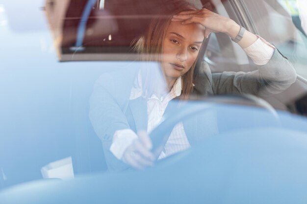 Jonge zakenvrouw voelt zich geïrriteerd tijdens het autorijden en vast komen te zitten in een verkeersopstopping Het uitzicht is door het glas