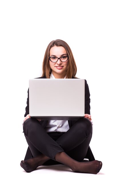 Jonge zakenvrouw zittend op de vloer en met behulp van laptop geïsoleerd op een witte muur