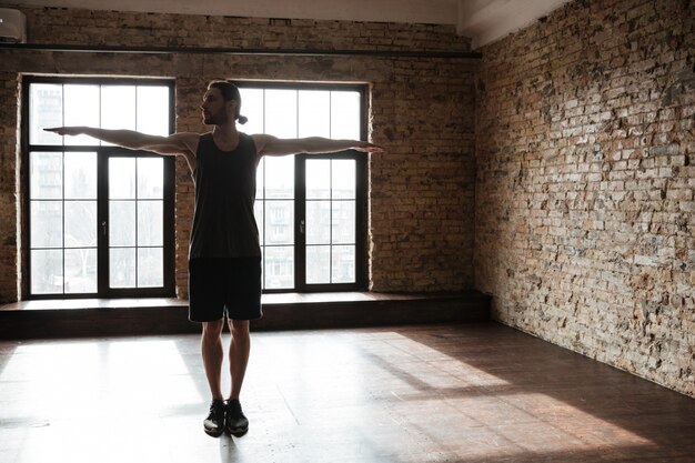 Jonge zekere sportman die bij de gymnastiek opwarmen