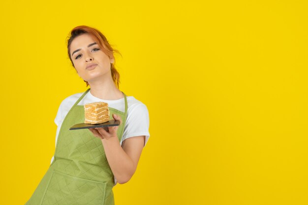 Jonge zelfverzekerde roodharige met cakeplak op gele muur