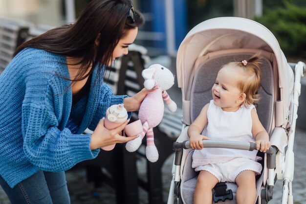 Jonge zus die met haar kleine schattige zusje buiten loopt, geef haar water