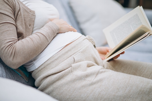 Jonge zwangere vrouw die een boek thuis leest