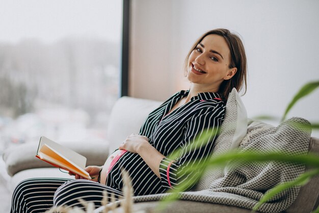 Jonge zwangere vrouw die thuis notitieboekje leest