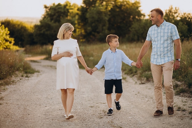 Jonge zwangere vrouw met man en zoon op zonsondergang