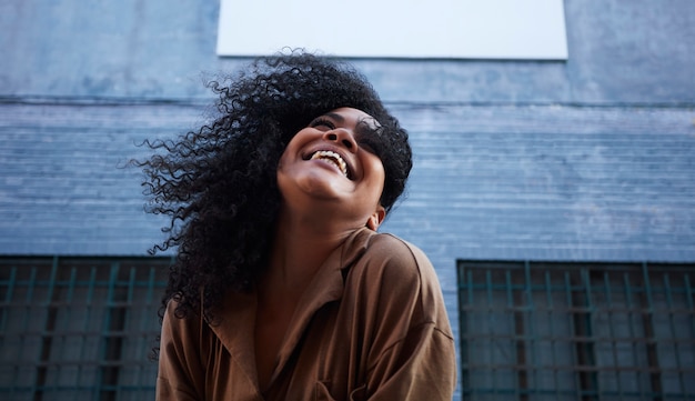 jonge zwarte vrouw met afro haar lachen en genieten