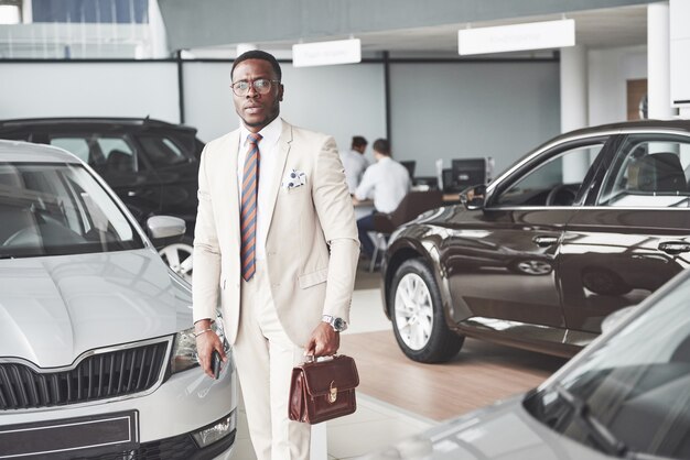 Jonge zwarte zakenman op autosalon. Auto verkoop en huur concept.