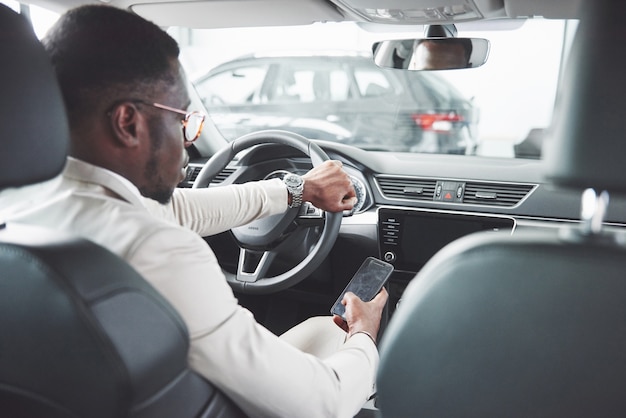 Jonge zwarte zakenman testrit nieuwe auto. rijke afro-amerikaanse man.