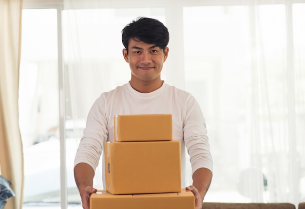 Jongelui die de logistische leveringsmens glimlachen die de doos houdt