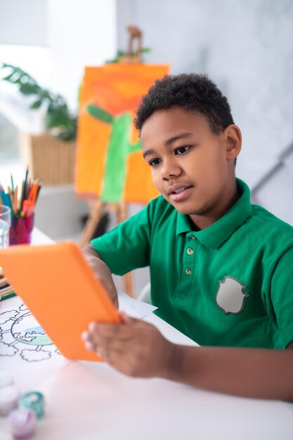 Jongen aandachtig kijkend naar tablet zittend aan tafel