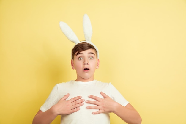 Jongen als paashaas op gele studiomuur