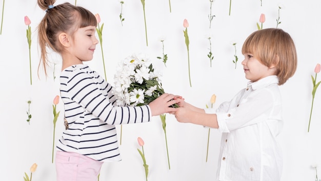 Gratis foto jongen die bloemen geeft aan leuk meisje