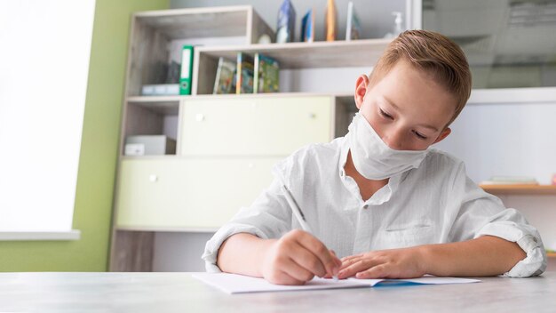 Jongen die een medisch masker draagt in de klas met een kopie ruimte