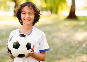 Gratis foto jongen die een voetbal met exemplaarruimte houdt