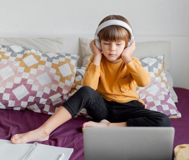 Jongen die hoofdtelefoons draagt en leert