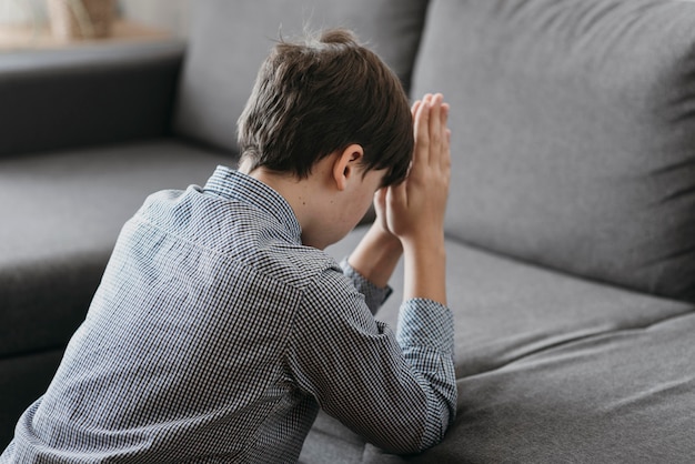 Gratis foto jongen die op de bank thuis bidt