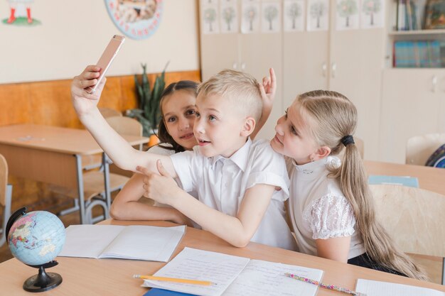 Jongen die selfie met meisjes bij bureau nemen