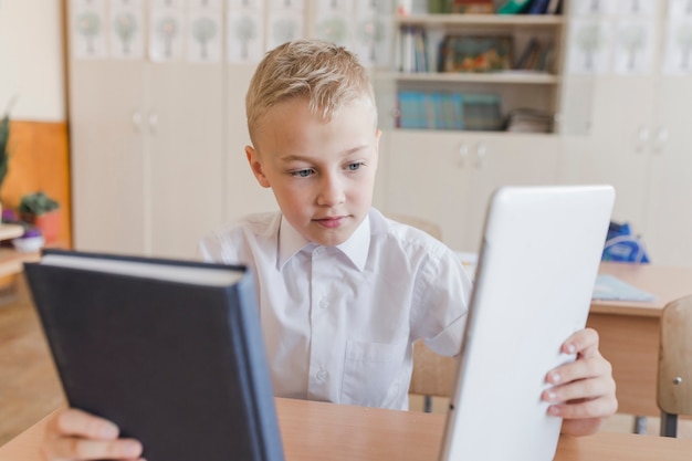 Jongen die tussen boek en tablet bij les kiest