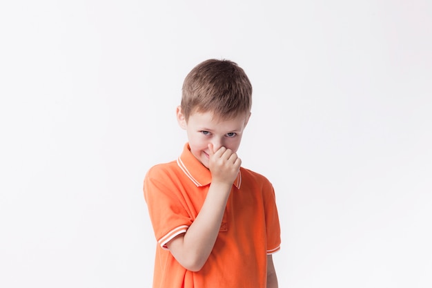 Jongen die zijn neus met vingers sluit die camera op witte achtergrond bekijken