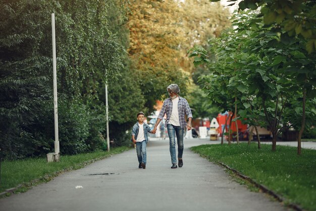 Jongen en grootvader wandelen in het park. Oude man speelt met kleinzoon.