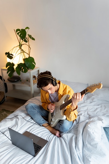 Gratis foto jongen gitaar spelen thuis hoge hoek