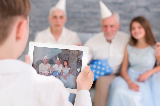 Jongen het klikken familiefoto door digitale tablet thuis