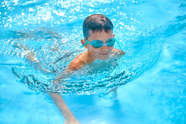 Jongen in beschermende brillen die in pool zwemmen