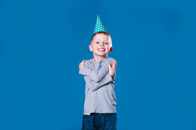 Jongen in feestmuts omarmen zichzelf