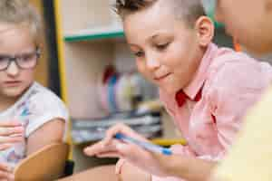 Gratis foto jongen in roze shirt leunend op tafel