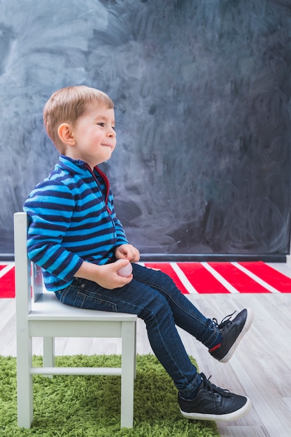 Gratis foto jongen lachen zittend op een stoel