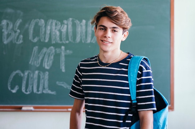 Gratis foto jongen lachend en poseren met schoolbord