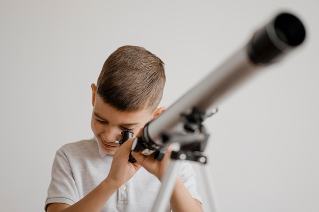 Gratis foto jongen met behulp van een telescoop in de klas