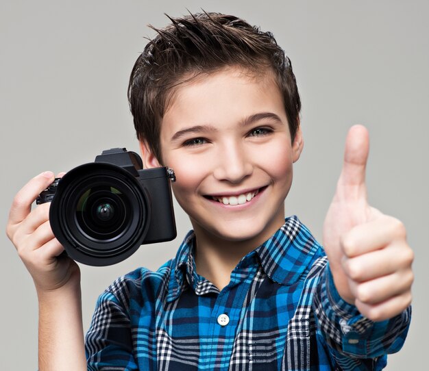 Jongen met camera die foto's maakt. Gelukkige pretjongen met dslr-camera die de duim toont