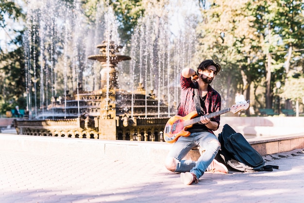 Gratis foto jongen met elektrische gitaar op fontein