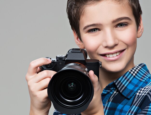 Jongen met fotocamera die foto's maakt. Portret van de blanke jongen met digitale camera in handen