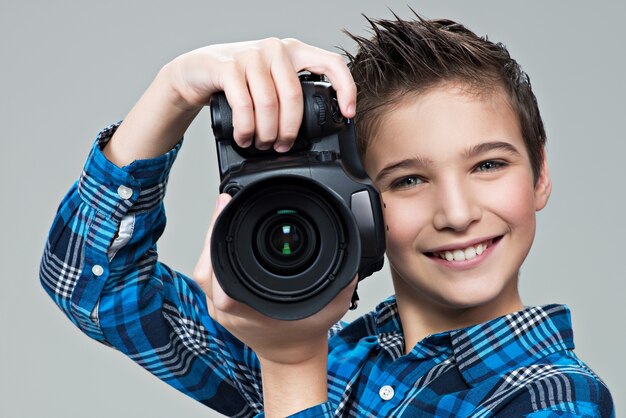 Jongen met fotocamera die foto's maakt. Portret van de blanke jongen met digitale camera in handen