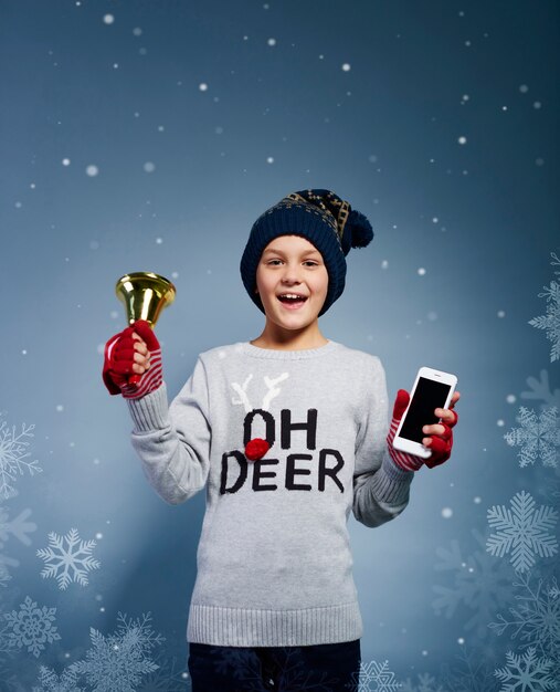 Jongen met Kerstmisklok en mobiele telefoon