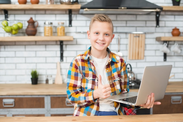 Gratis foto jongen met laptop in de keuken