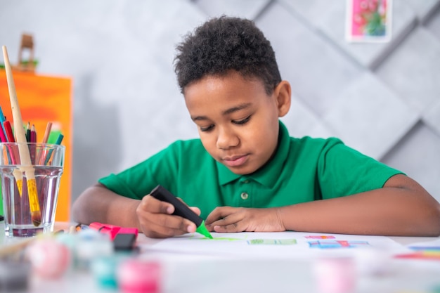 Jongen met marker in de hand aan tafel zitten