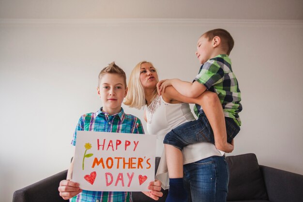 Jongen met moederdag poster met zijn broer en zijn moeder op de achtergrond