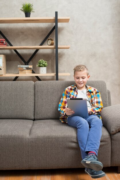 Jongen met tablet op de bank