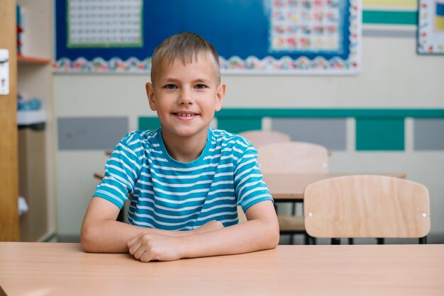 Jongen poseren aan tafel in de klas