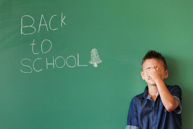 Jongen sluiten gezicht in de klas