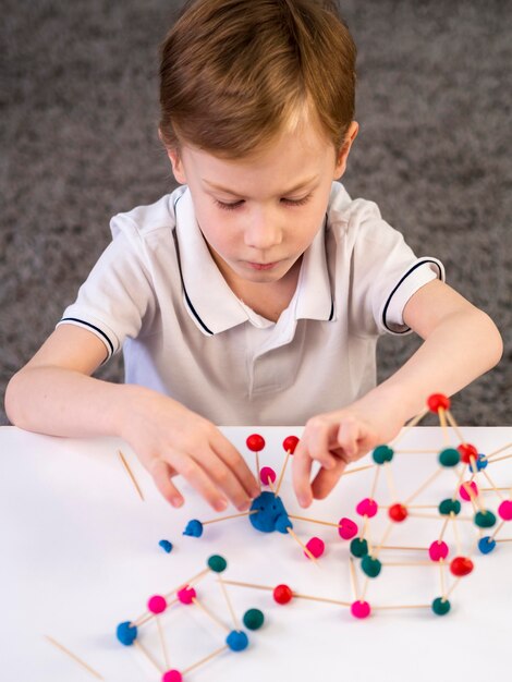 Jongen speelt met kleurrijke atomen spel