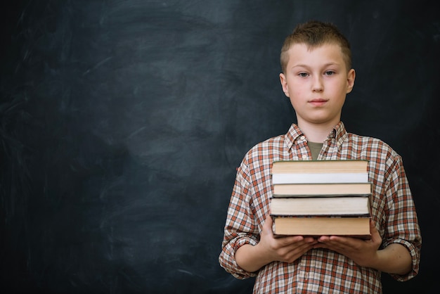 Gratis foto jongen staande boeken houden