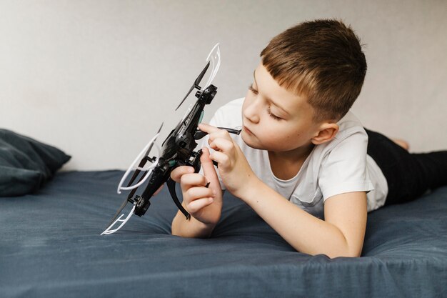 Jongen zit in het bed en speelt met drone