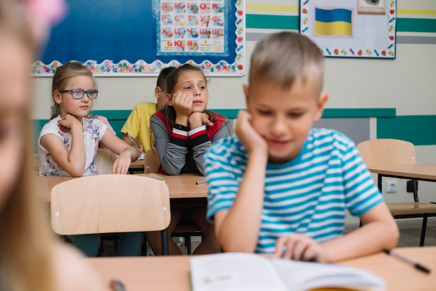 Gratis foto jongen zit leunend aan de hand lezen