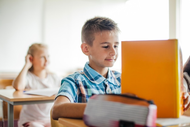 Jongen zitten op school bureau lezen handboek